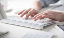 Hands Typing On Computer Keyboard In Office Desk.
