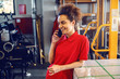 © Dusan Petkovic - Young cheerful Caucasian female employee with curly hair standing in printing shop and talking on the smart phone.