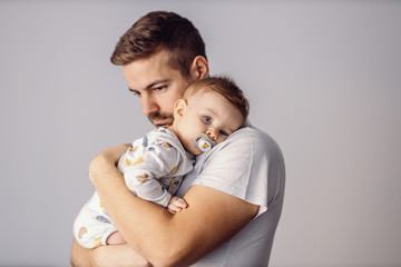 Wall Mural - Young attractive caring father holding his beloved little son, singing song to him and having fun.