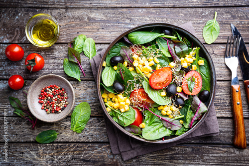Healthy salad, leaves mix salad with mangold, spinach and vegetables in the plate over wooden background, top view Tableau sur Toile