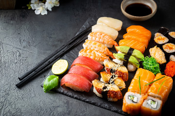 Wall Mural - Set of sushi and maki with soy sauce over black background. Top view with copy space