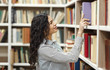 © Prostock-studio - Smiling latina woman taking book at library