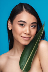 Wall Mural - Positive smiling asian young woman with green plant leaf.