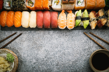 Wall Mural - Set of sushi and maki with soy sauce over stone gray background. Top view with copy space