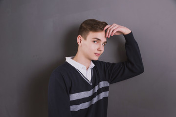 Wall Mural - Lifestyle photo of a young brown-haired man on a light background, a beautiful young guy in a shirt and sweater