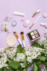 Wall Mural - Natural woman make up cosmetics with spring white lilac bloom. Top view. Spring female decorative cosmetics on purple background. Natural organic cosmetic for make up. Cosmetic and brushes in blossom