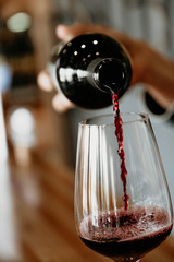 man pours red wine in a glass