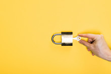 Top View Of Man Touching Key In Metallic Padlock Isolated On Yellow