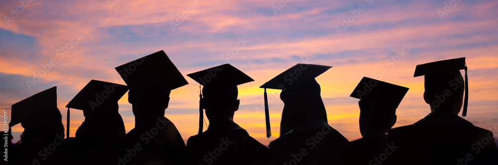 Obraz Silhouettes of students with graduate caps in a row on sunset background. Graduation ceremony at university web banner. fototapeta, plakat