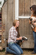 © MACO - Young western girl on a ranch petting a goat standing next to mother. Bridger, Montana, USA