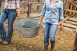 © MACO - Close-up of two young western girls on a ranch, carrying a big washing bucket. Bridger, Montana, USA
