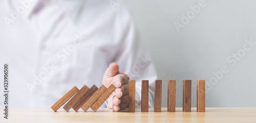 Cuadros en Lienzo Hand stopping wooden domino business crisis effect or risk protection concept