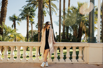 Beautiful girl resting and enjoying vacation in Monaco. Woman in wearing sunglasses posing  on a background of palm trees. Fascinating european female model posing with pleasure in exotic country. 