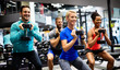 Group of young happy fit people doing exercises in gym