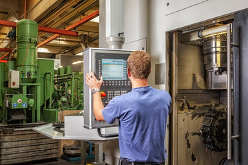 Skilled worker controlling a digitally programmed machine tool