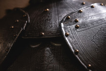 Close Up Detail Background With Armour Of The Medieval Knight. Metal Protection Of The Soldier. Steel Plate. Rivets And Engraving, Dark Light