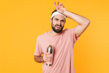 Sticker - Image of tired athletic young man in t-shirt holding water bottle