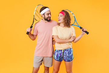 Canvas Print - Portrait of athletic young couple holding rackets while playing tennis