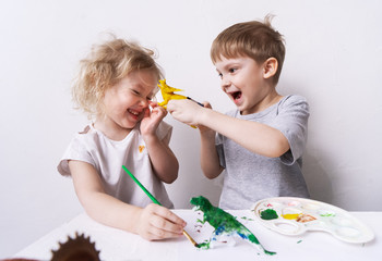 children boy and girl laugh cheerfully play and paint with toy and brush figures of toy dinosaurs.