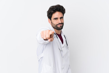 Young handsome man with beard over isolated white background wearing a doctor gown and pointing to the front