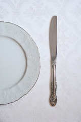 The texture on the white fabric. a linear pattern. White plate and knife. tableware