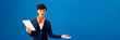 © LIGHTFIELD STUDIOS - panoramic shot of smiling african american flight attendant holding digital tablet and pointing with hand isolated on blue