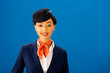 © LIGHTFIELD STUDIOS - smiling african american flight attendant looking at camera isolated on blue
