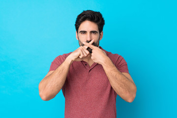 Wall Mural - Young handsome man with beard over isolated blue background showing a sign of silence gesture