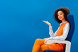 © LIGHTFIELD STUDIOS - smiling african american in retro dress pointing with hand isolated on blue