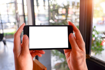 Mockup picture of business woman’s hands holding smart phone with white blank screen in modern place.