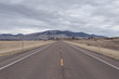 © Richard - Empty roadway leading line to large rolling hills with sparse tree coverage
