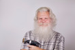 Senior thickset Caucasian smiling man with splendid grey hair and beard on grey background with electric drill with grinding head in hand. Attractive elderly European handsome happy people close up.