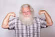 Senior thickset Caucasian happy man with splendid grey hair and beard on grey background, demonstrating his big biceps. Attractive elderly European handsome smiling people close up. Beautiful portrait