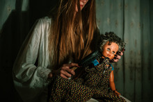 Girl In Night Gown Combing Old Dolls Hair. Bizarre, Disturbing Concept