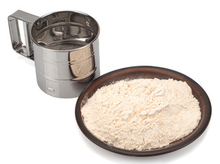 Metal flour sifter and flour in plate Isolated on a white background