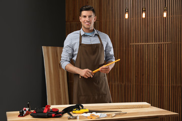 Wall Mural - Handsome carpenter with folding rule near wooden wall