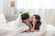© Sathaporn - Happy young asian married couple covered with soft warm white blanket together on comfortable bed in bedroom