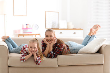 Poster - Happy mother and little daughter having fun on sofa at home