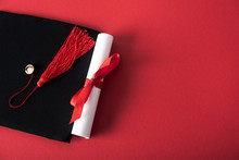 Top View Of Diploma With Beautiful Bow And Graduation Cap With Tassel On Red Background