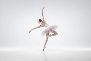 Wall Mural - Graceful classic ballerina dancing isolated on white studio background. Woman in tender clothes like a white swan characters. The grace, artist, movement, action and motion concept. Looks weightless.