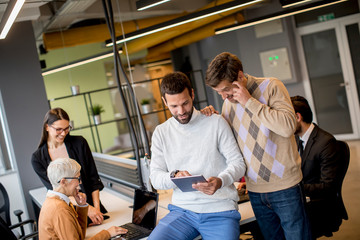 Wall Mural - Business people working and communicating while standing in  the office together with colleagues sitting in the background