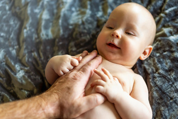 Gentle dad or grandpa touch. Big love for small baby. Two different generations, family values, sustainability. Closeup, copy space, selective focus.