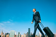 © PeskyMonkey - Traveling businessman walking with his wheeled suitcase across the city skyline