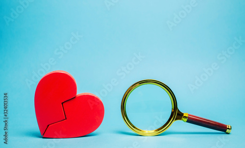 Red heart and a magnifying glass. The concept of finding love and relationships. Find a soul mate. Loneliness. Family psychologist services. Valentine\'s Day.