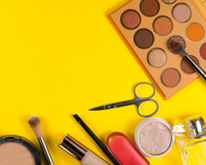 Various decorative makeup cosmetics on yellow background. Different beauty essentials for women.