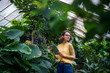 © Halfpoint - Young woman with tablet standing in botanical garden. Copy space.