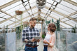 © Halfpoint - Man and woman researchers standing in greenhouse, using tablet.