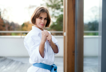 A young woman practising karate outdoors on terrace.