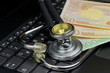 Costs and profit in medical digitalization. High angle view of stethoscope and euro banknotes on computer keyboard