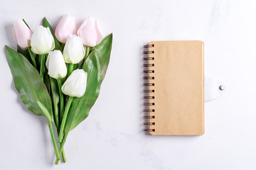 Canvas Print - Pastel Tulips with notebook on white marble background, copy space